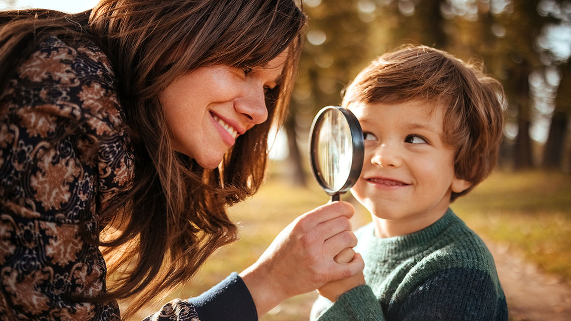 a mom and son look at each other through a magnifying glass