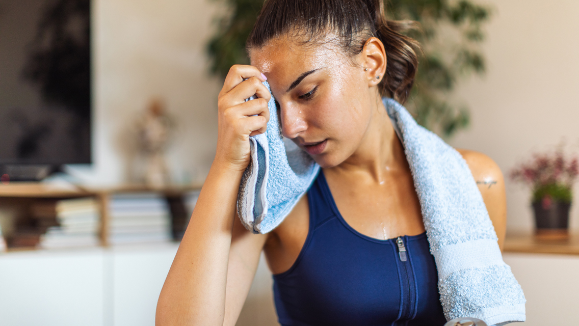 a woman wipes sweat off her face after working out