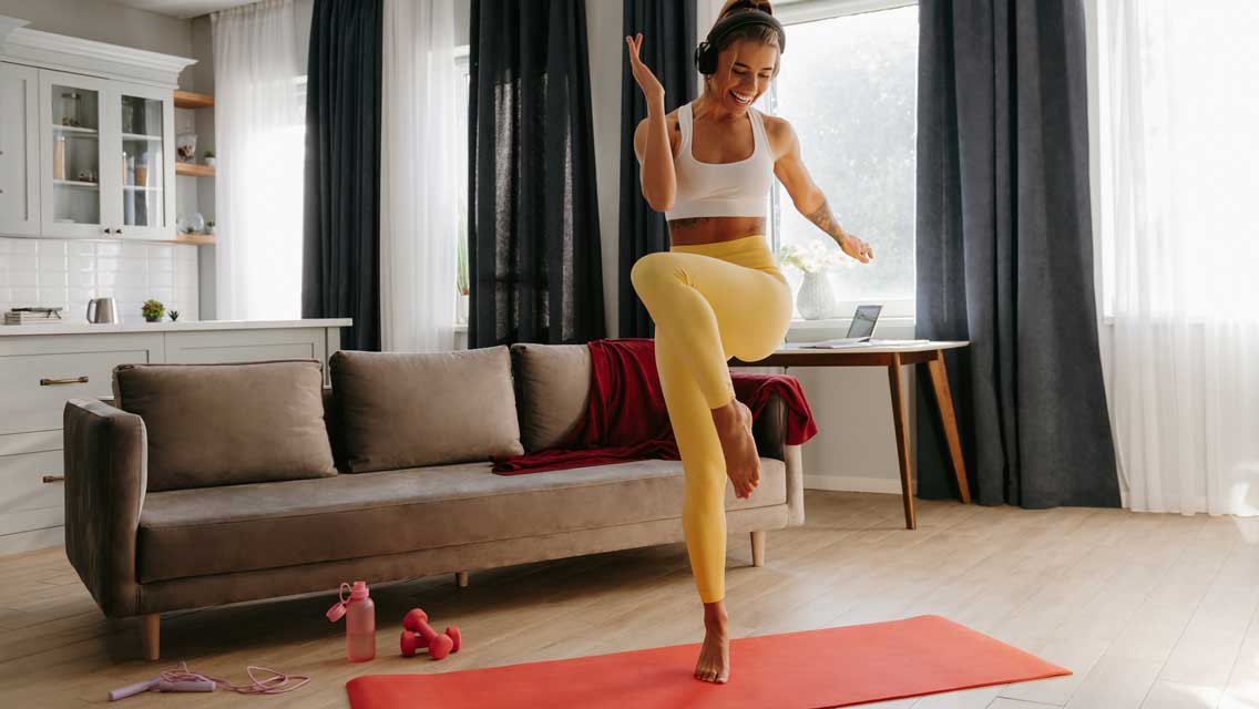 a woman dances on her yoga mat in her living room