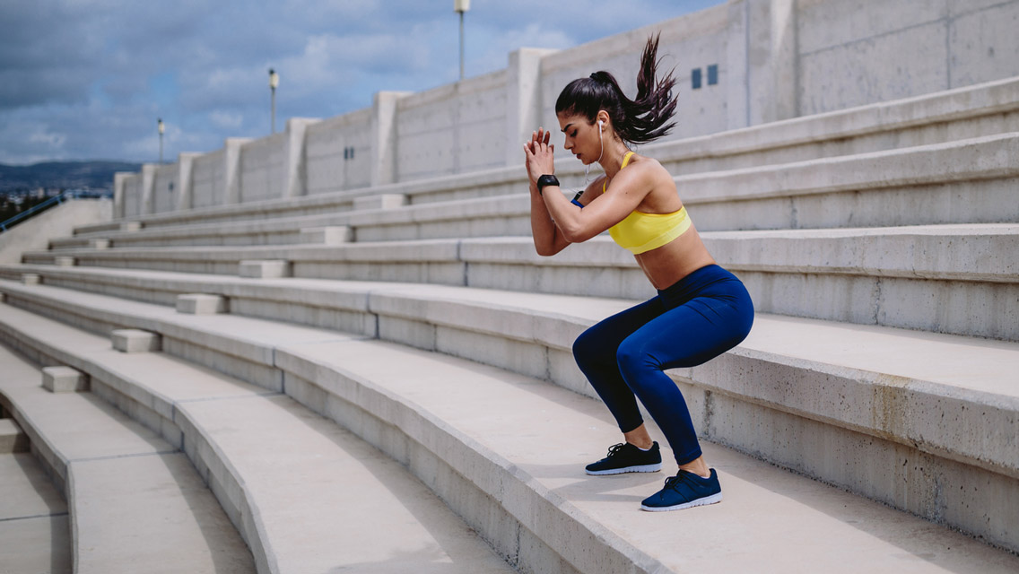 a woman jumps on a set of stadium stairs