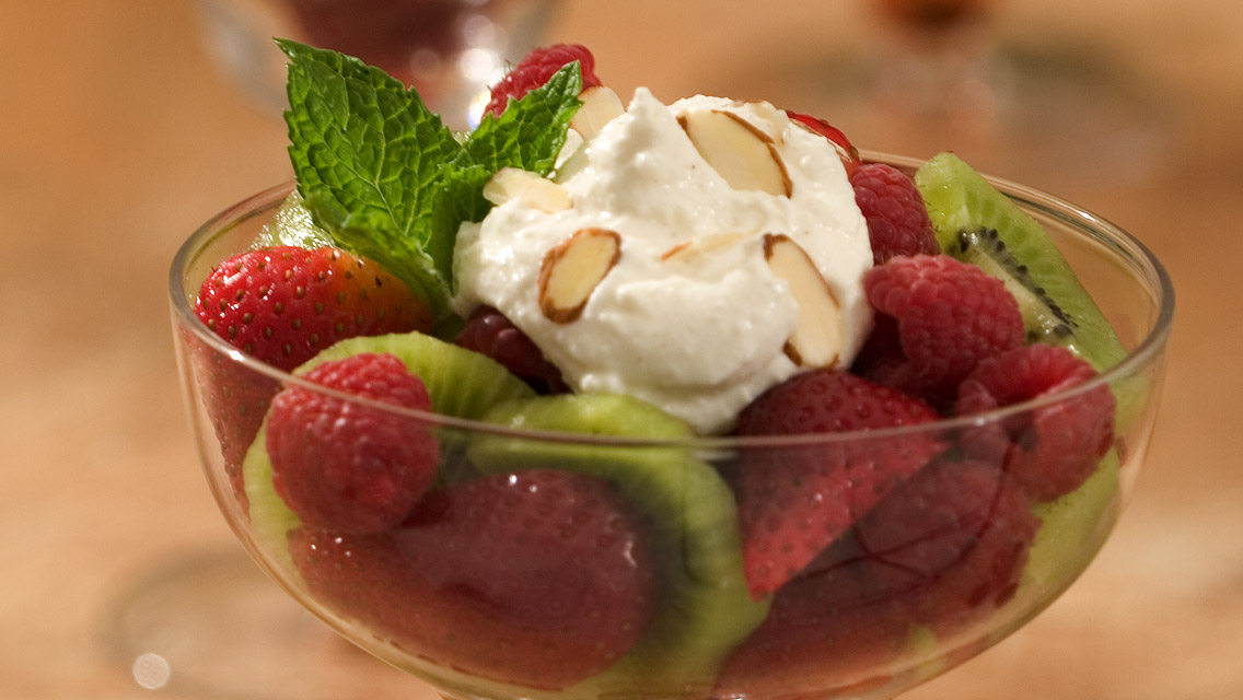 a dish of fresh fruit with a dollop of sweet cream