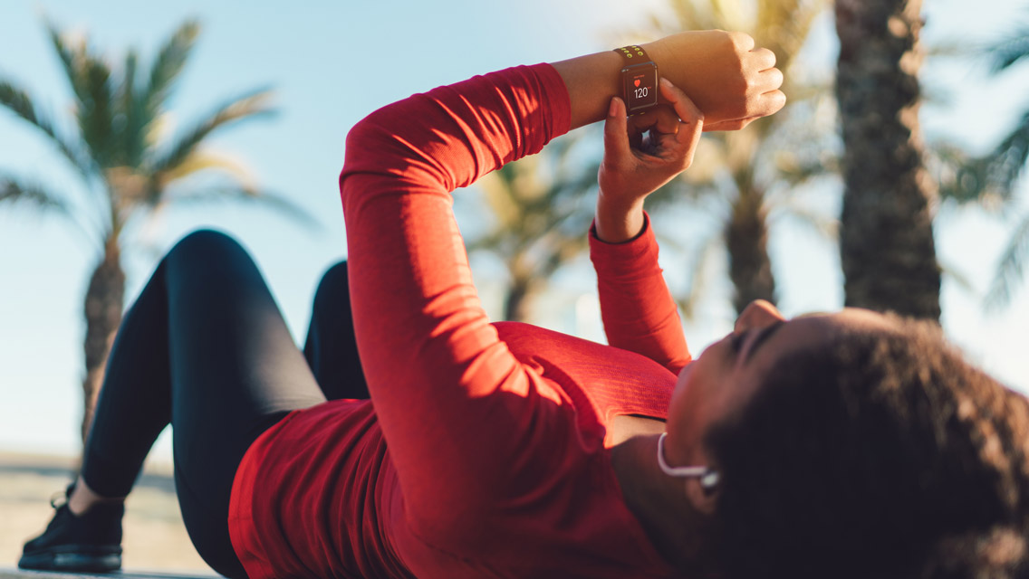 a woman lays on a bench looking at her heart rate monitor