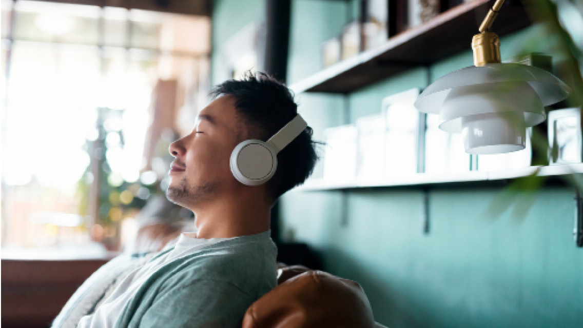 a man smiles with his eyes closed while listening to something on his headphones