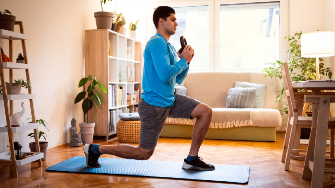 a man lunges with a kettlebell in his living room