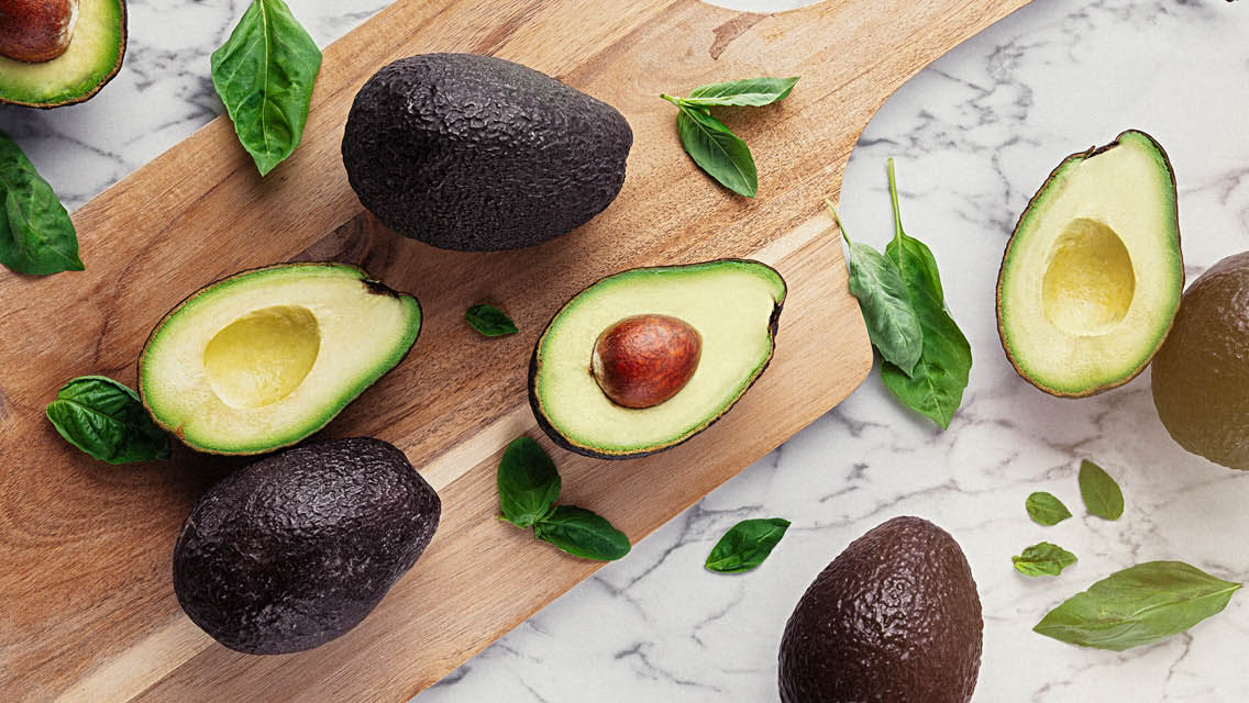 whole and half avocados displayed on a cutting board