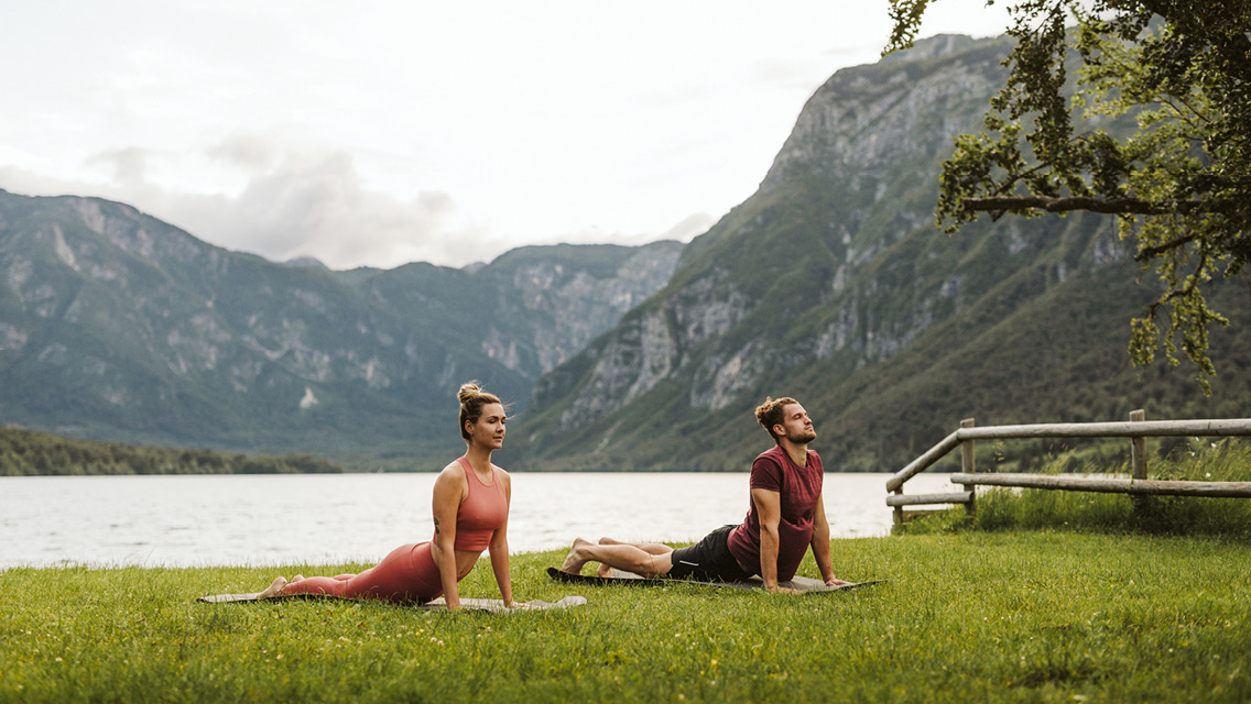 Couple doing yoga outside near the scenic lake