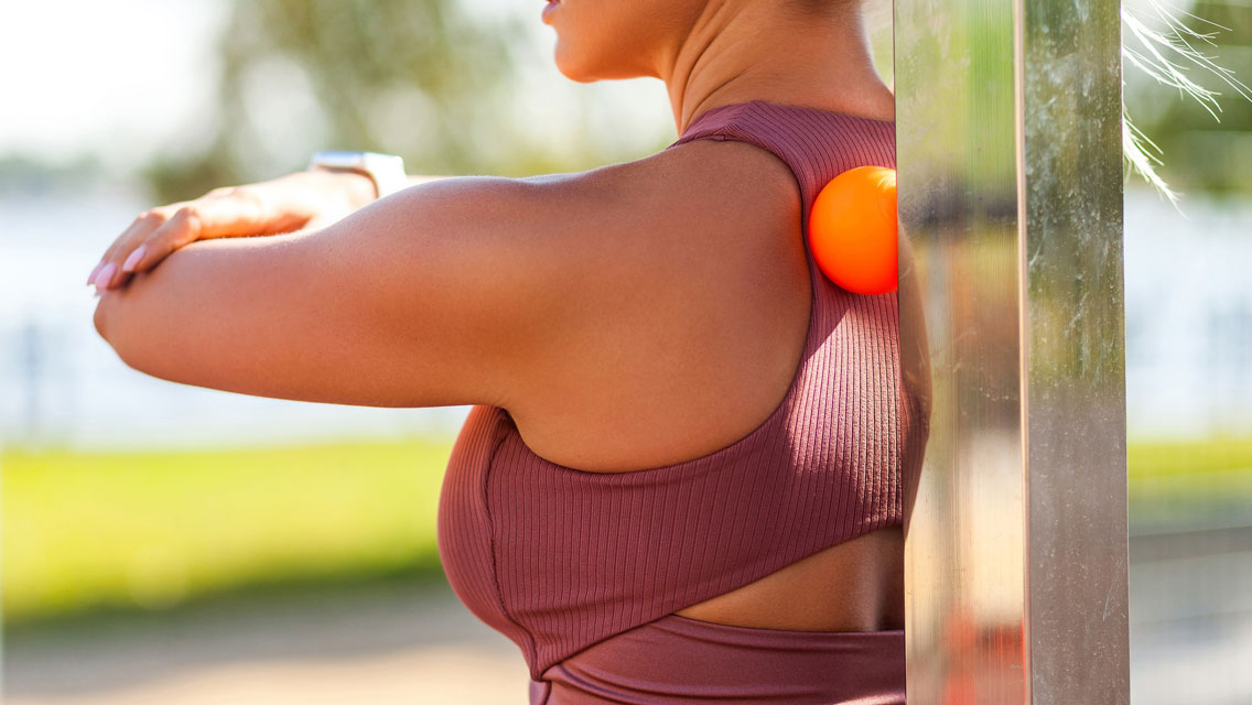 a woman uses a trigger release ball on her shoulder