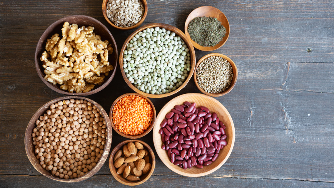 a variety of beans and legumes in wooden bowls