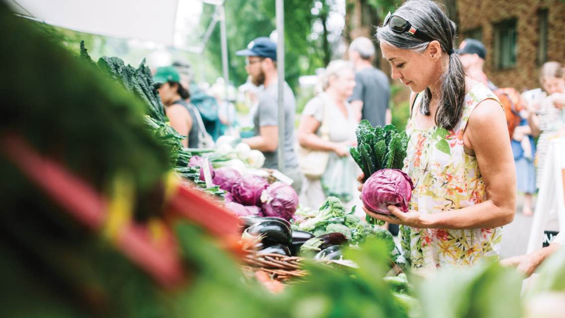Woman picking out produce at a farmers' market.