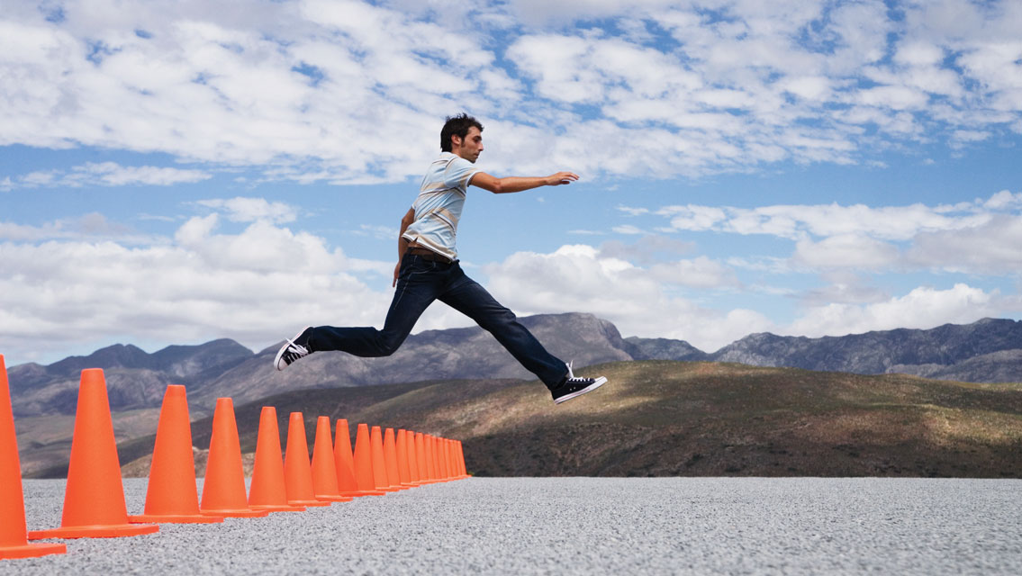 a man jumps over a line of orange cones