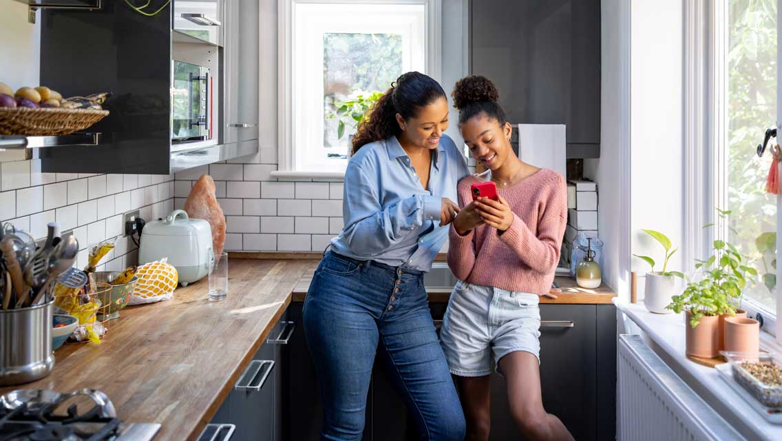 a mom talks in the kitchen with her teen daughter