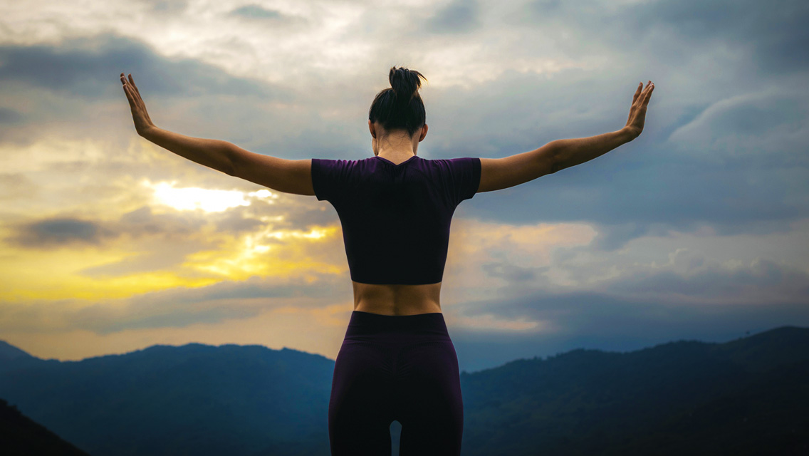 a woman stands with her back to the camera, arms out stretched as though pushing outside world away