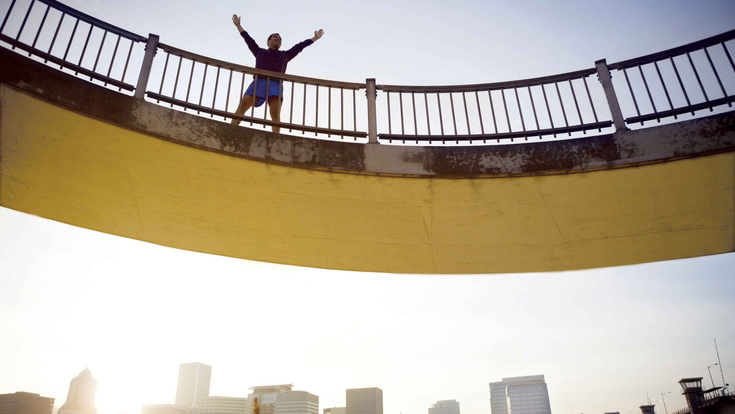 a man stands on top of a bridge with his arms up in a V