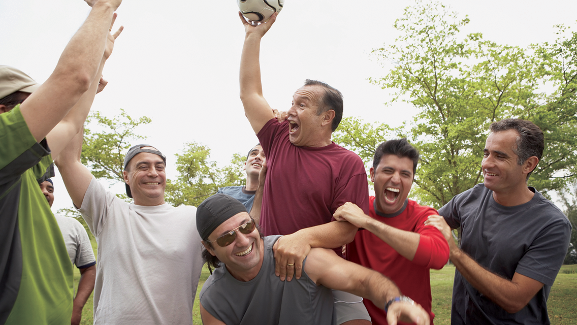 a group of men cheer after winning a soccer game