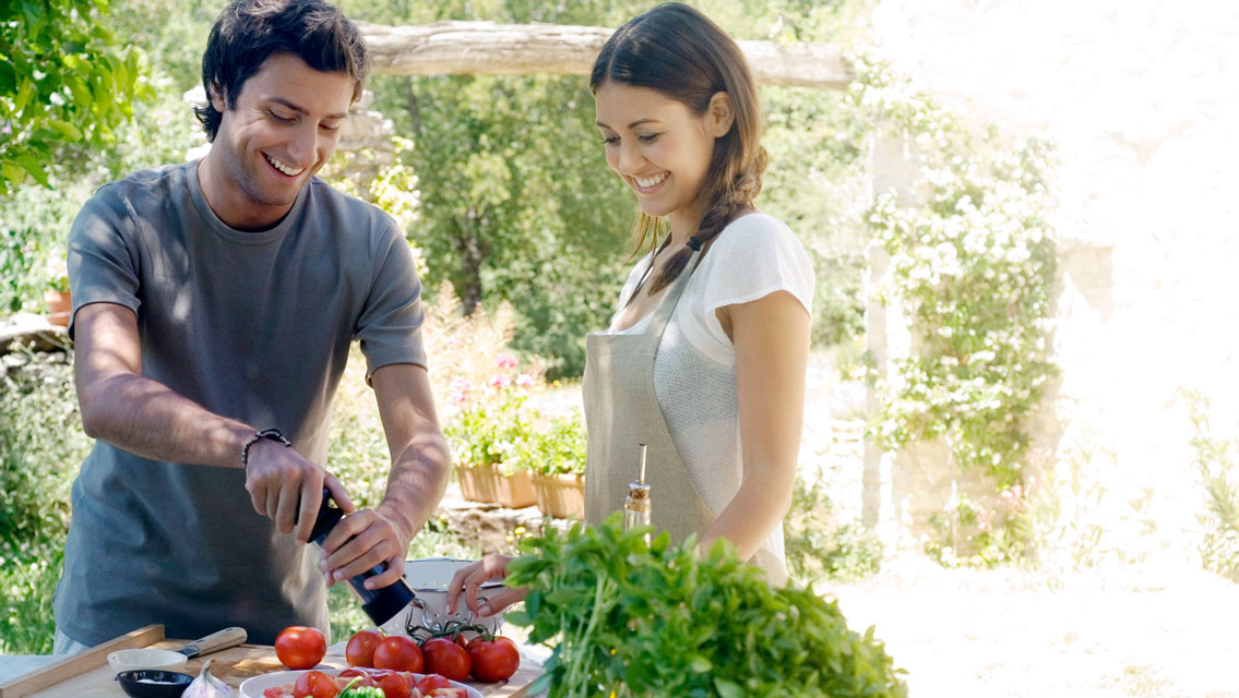 a man and woman prepare healthy food outside