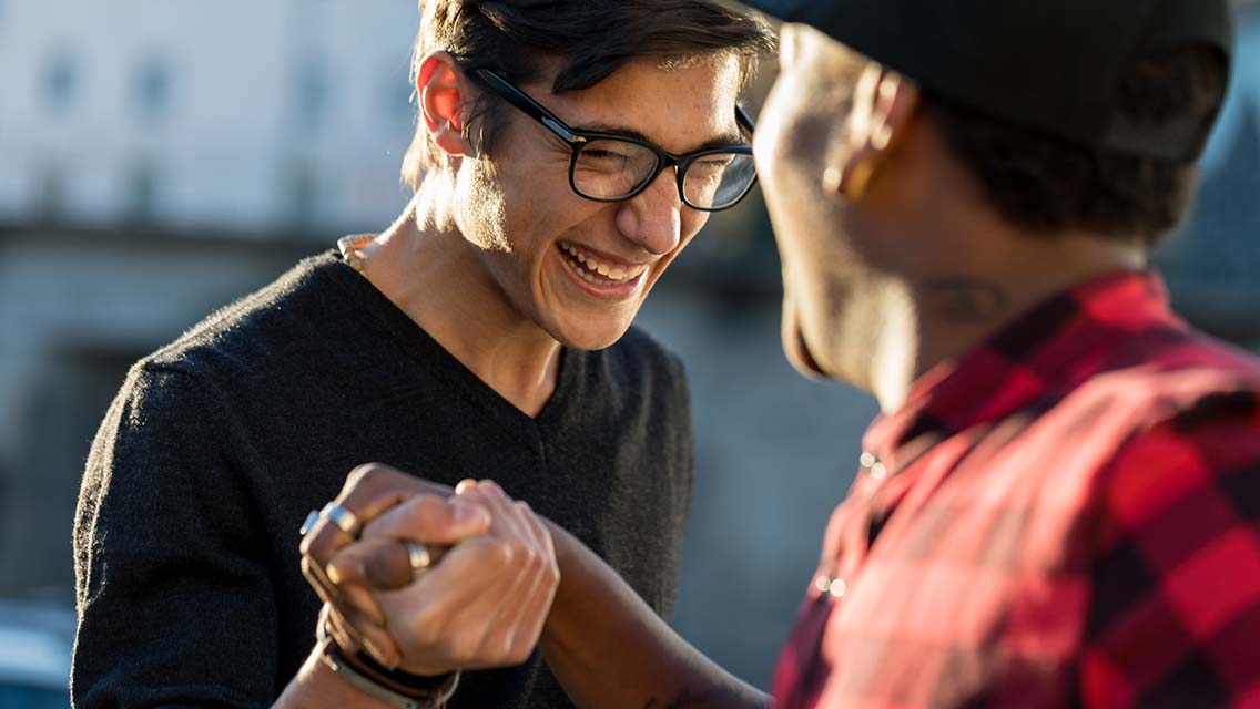 two guys shake hands while laughing.