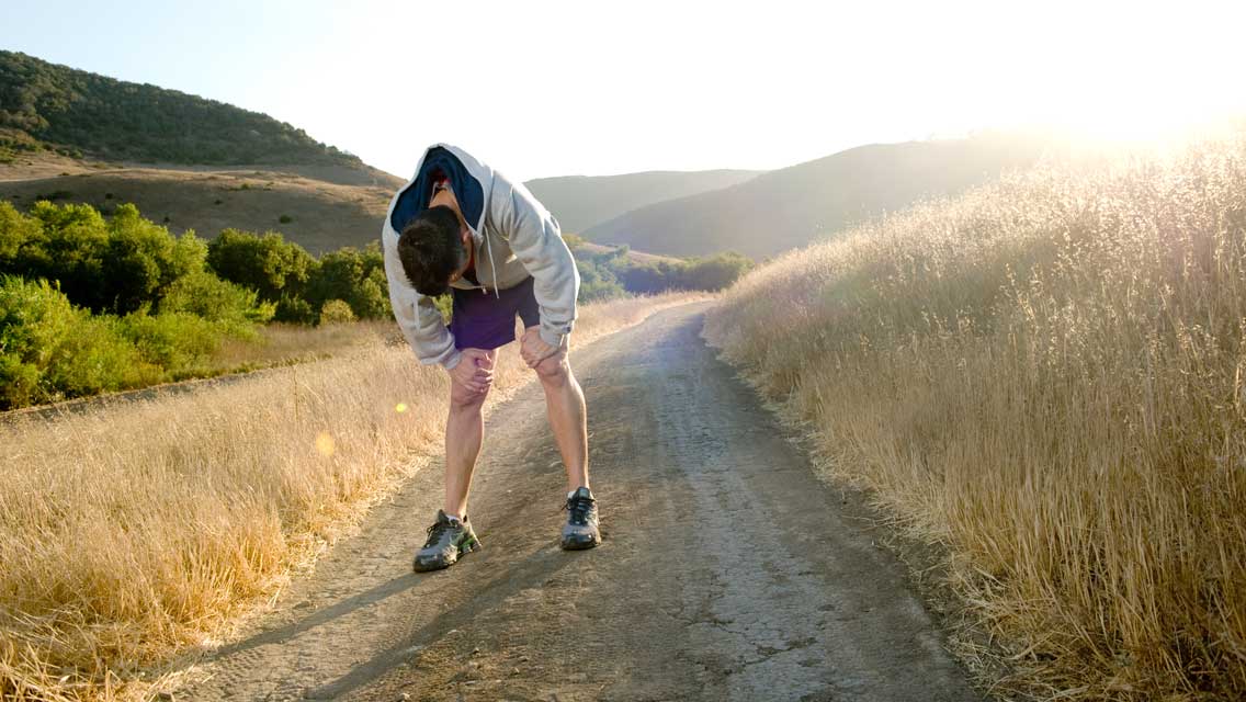 a man stands bent over, tired from running