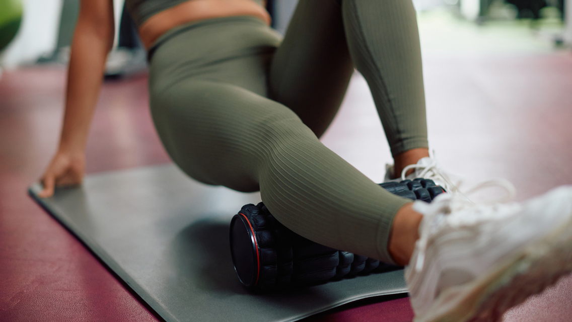 a woman foam rolls her calf