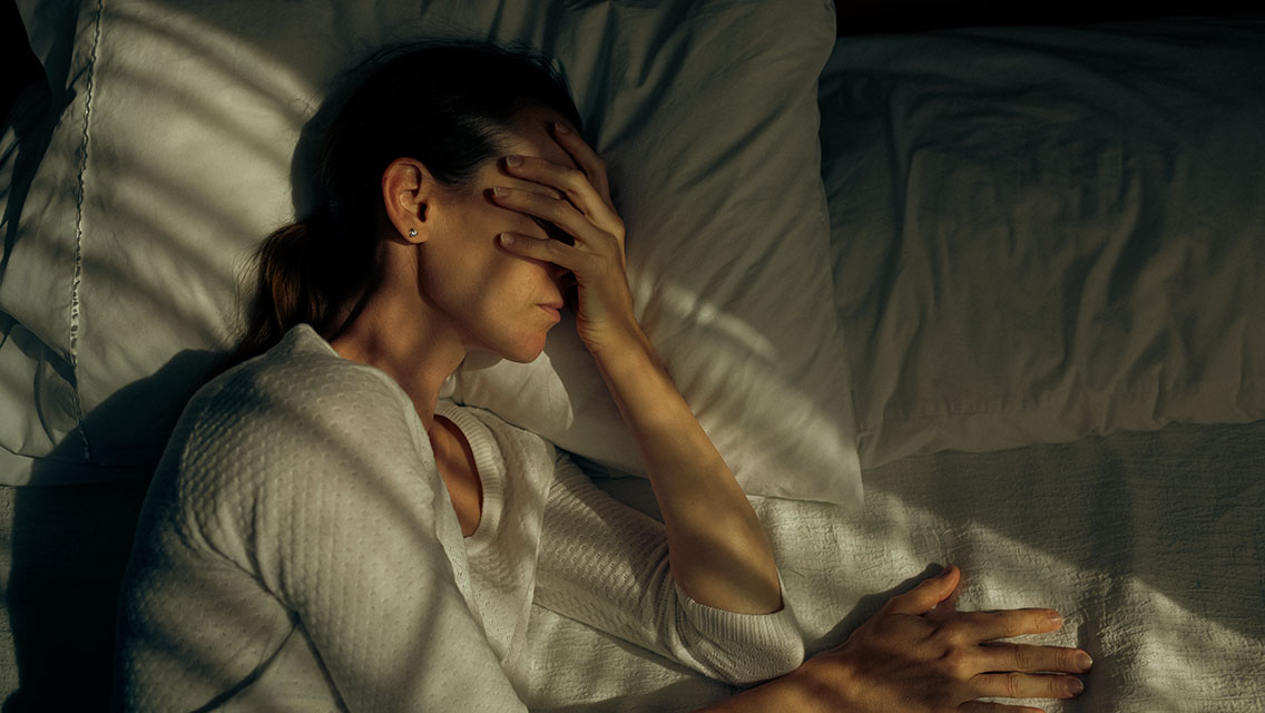 a woman in bed struggling with a headache