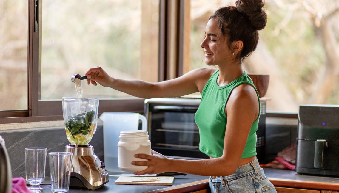 Young woman chopping ingredients for healthy smoothie in kitchen