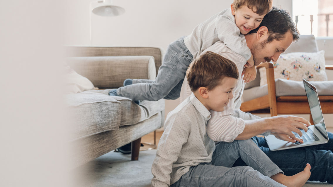 a dad works while his toddlers crawl over him