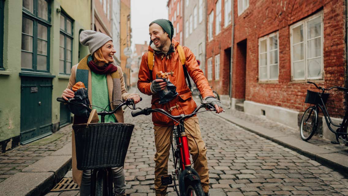 happy young couple eating Danish pastry while taking a short break cycling