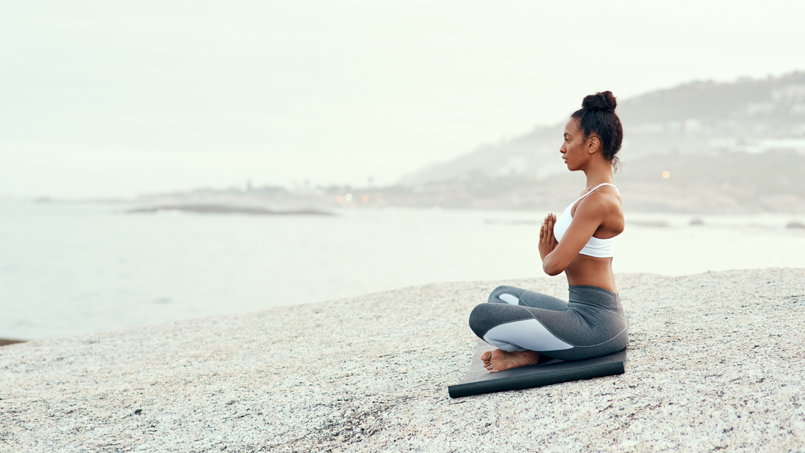 a woman meditates on a shoreline