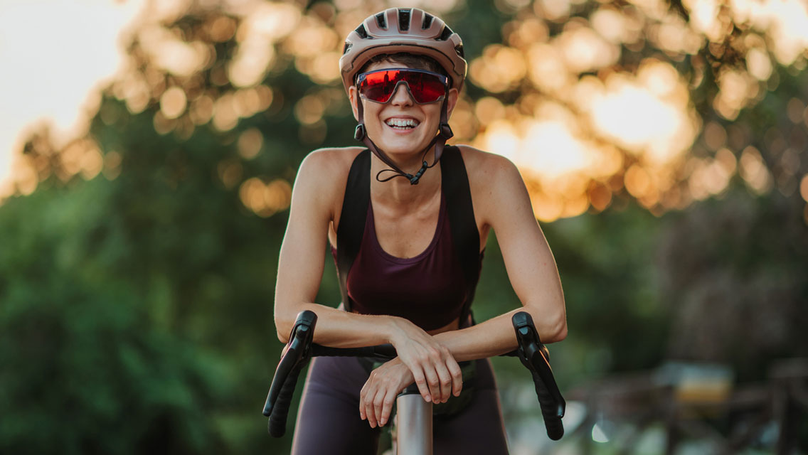 a woman smiles while resting on her bike