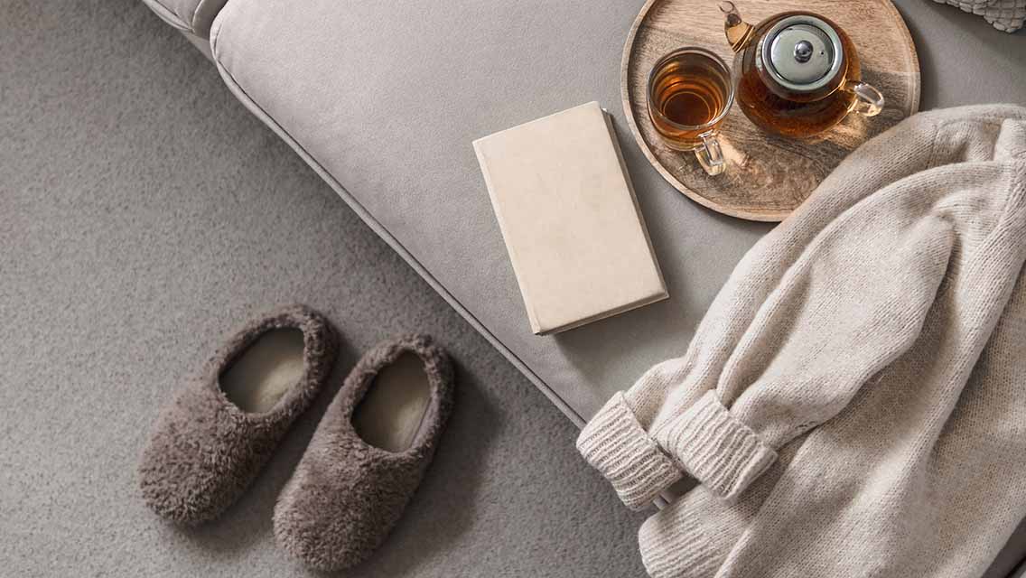 cozy shot of sweater, slippers, tea and a book