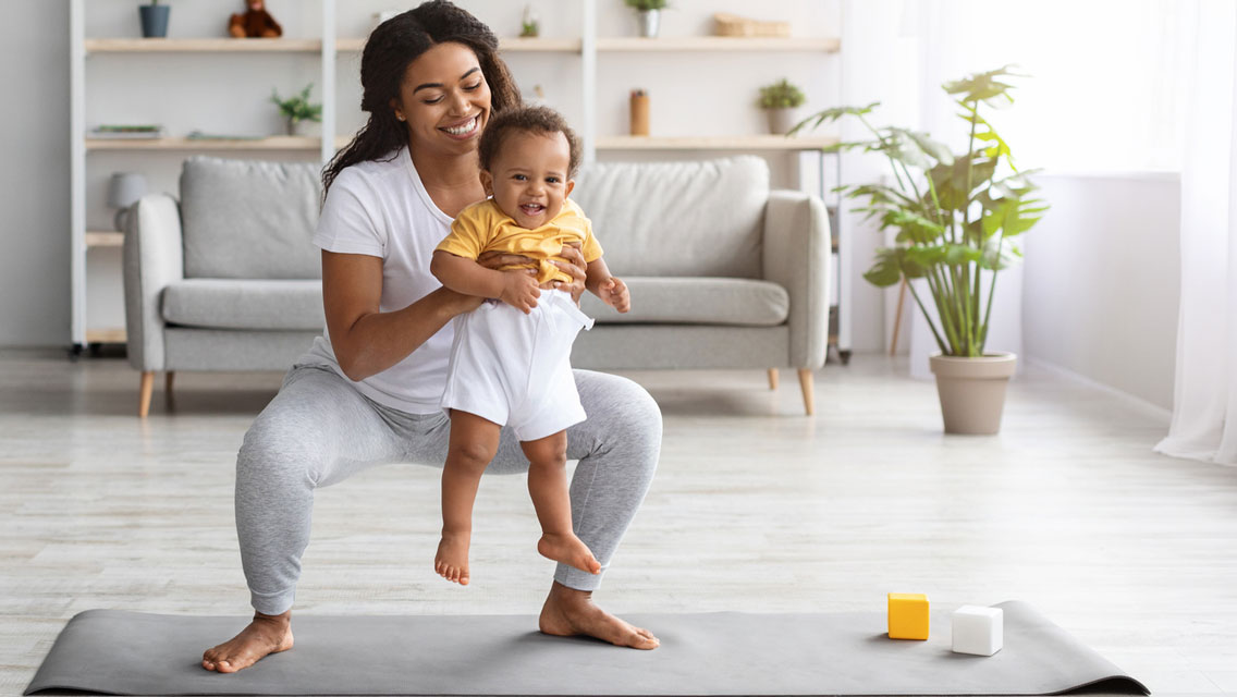 a mom performs a deep squat with her newborn