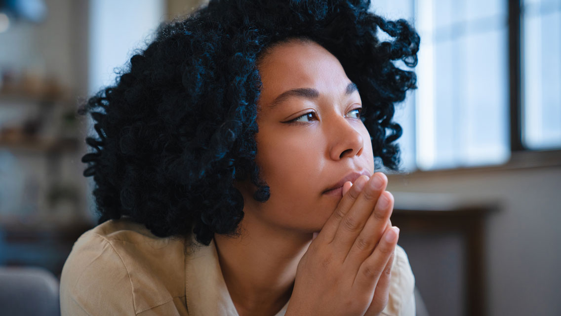 a woman looks apprehensive as she looks out a window