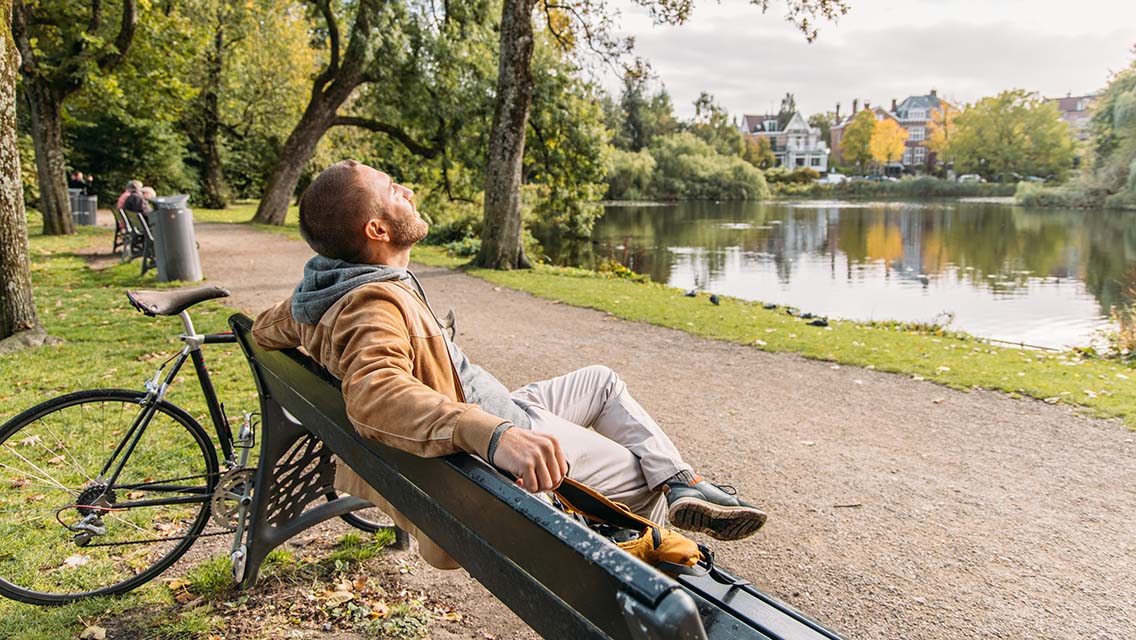 Man with a bicycle sitting on public park bench