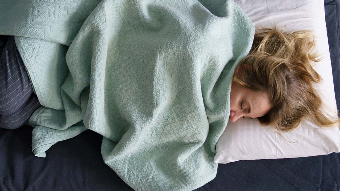 a woman sleeping with a mint green blanket