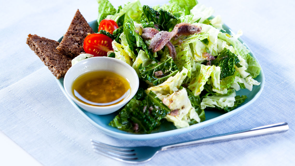 a plate of salad with a side of dressing