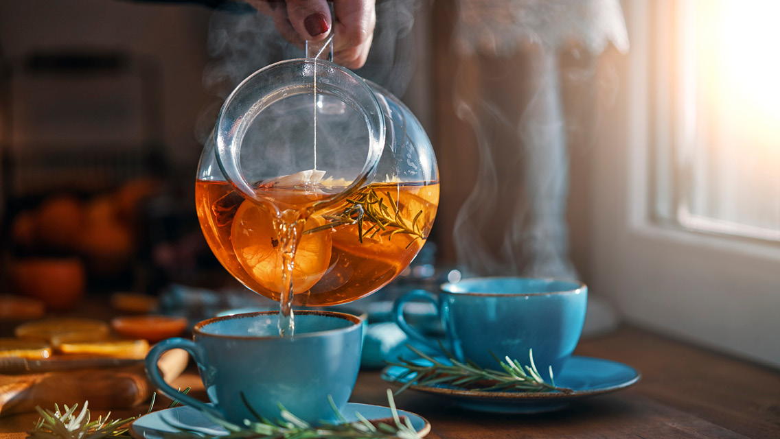 a person pours steaming tea into a cup