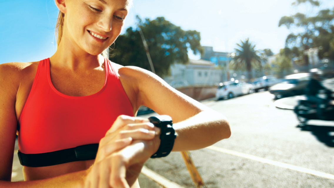 a woman looks at her smart watch while working out