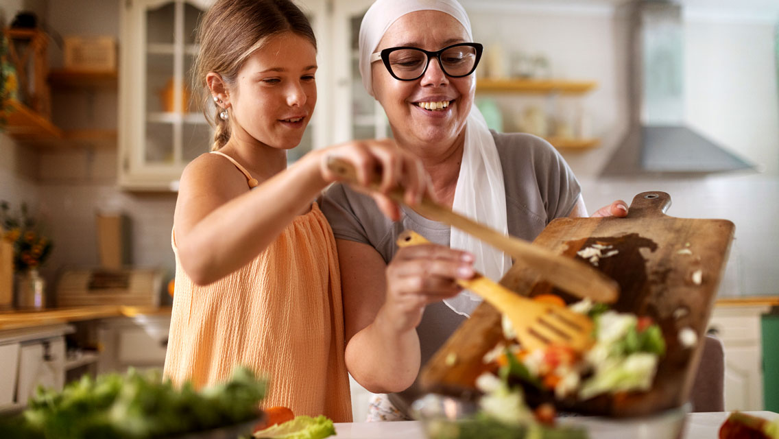 a woman with cancer makes a healthy salad with her daughter