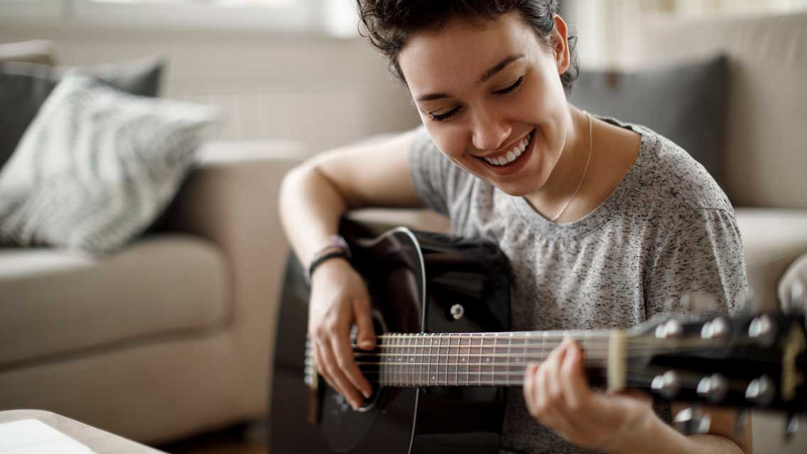 a woman practices guitar