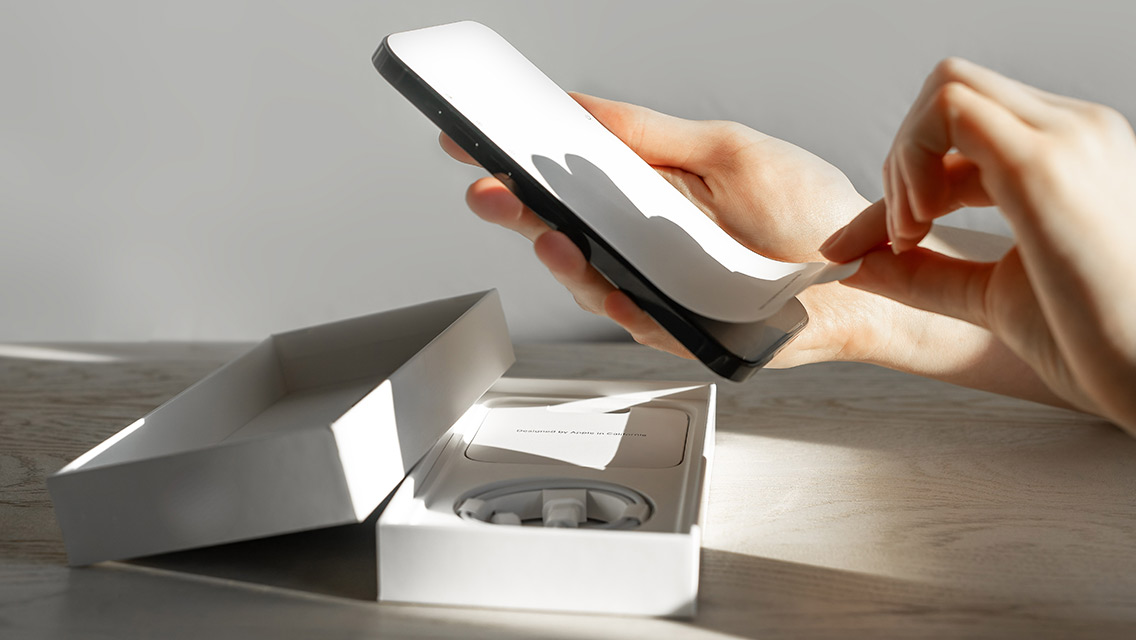 Person peeling off screen protector of smartphone