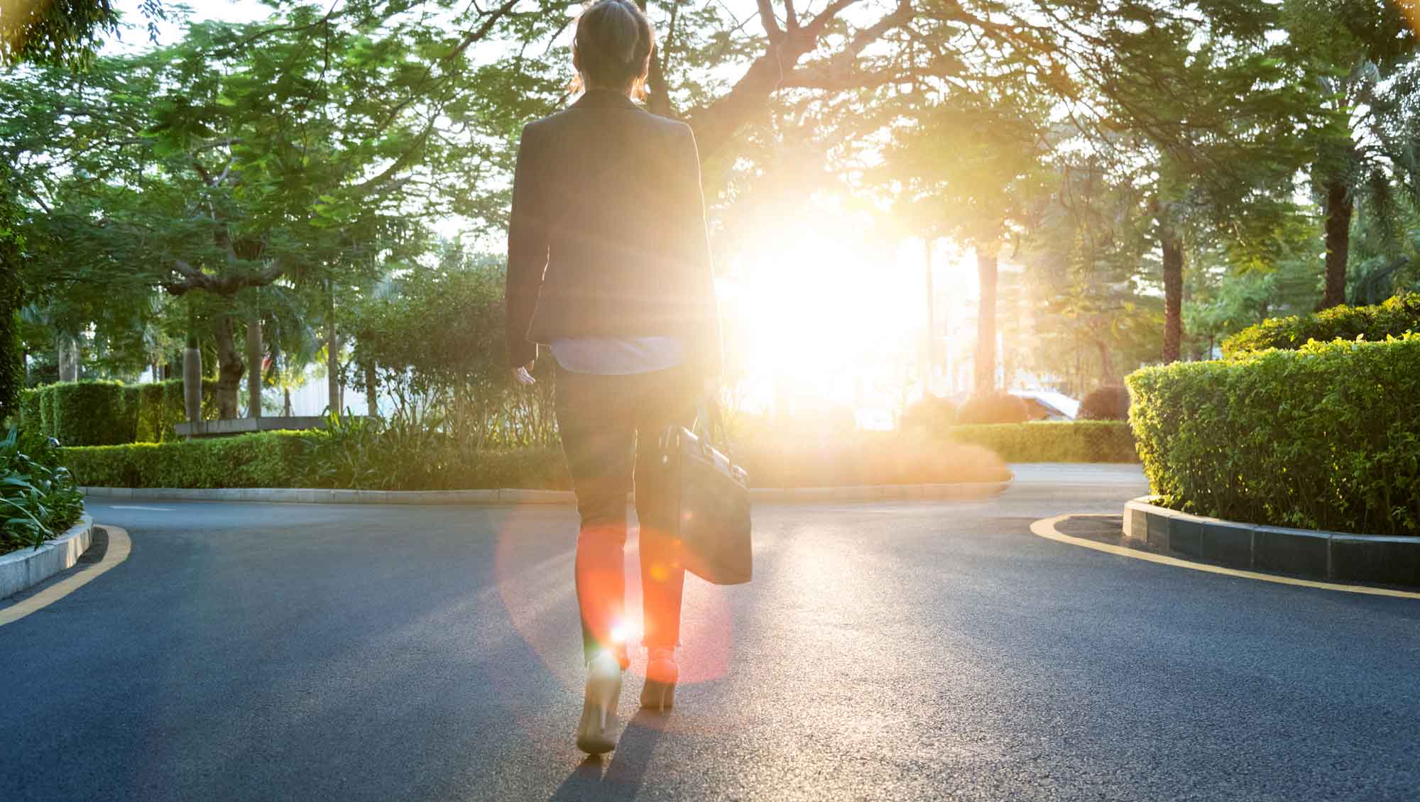 woman walking into bright sun with a trail that leads left and right