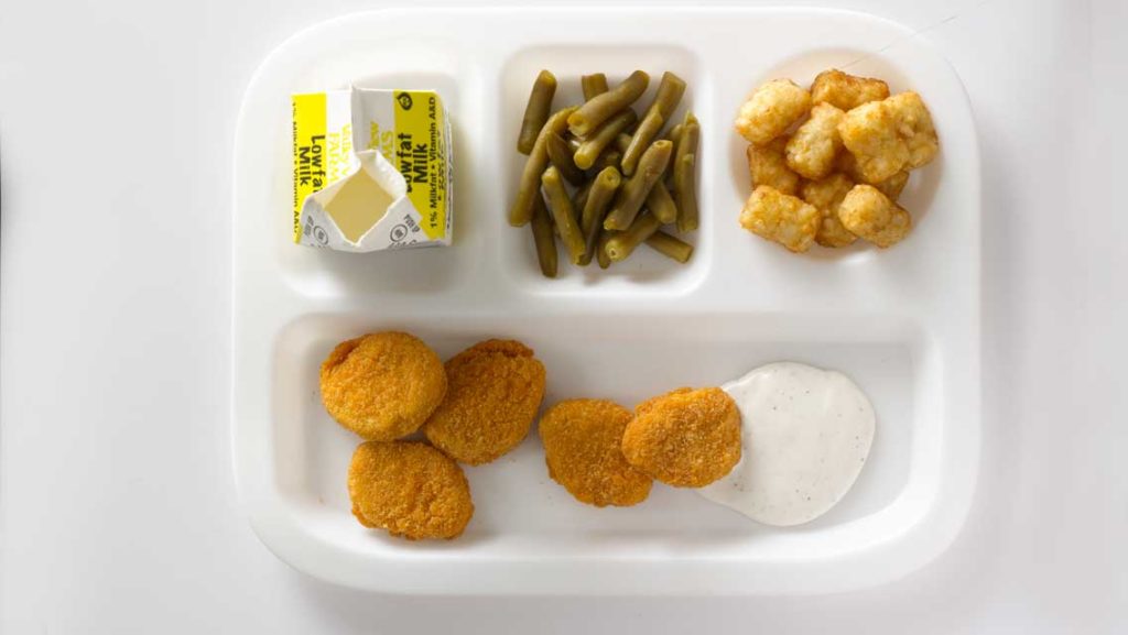tray of chicken nuggets, milks, beans and tots