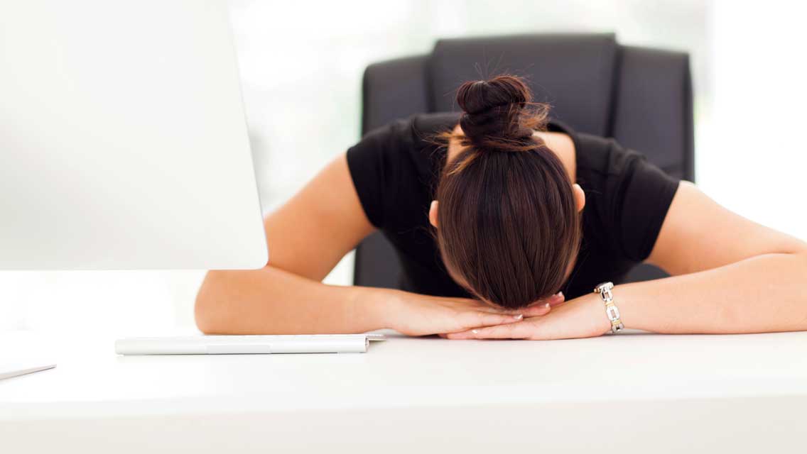 a woman lies with her head on her desk