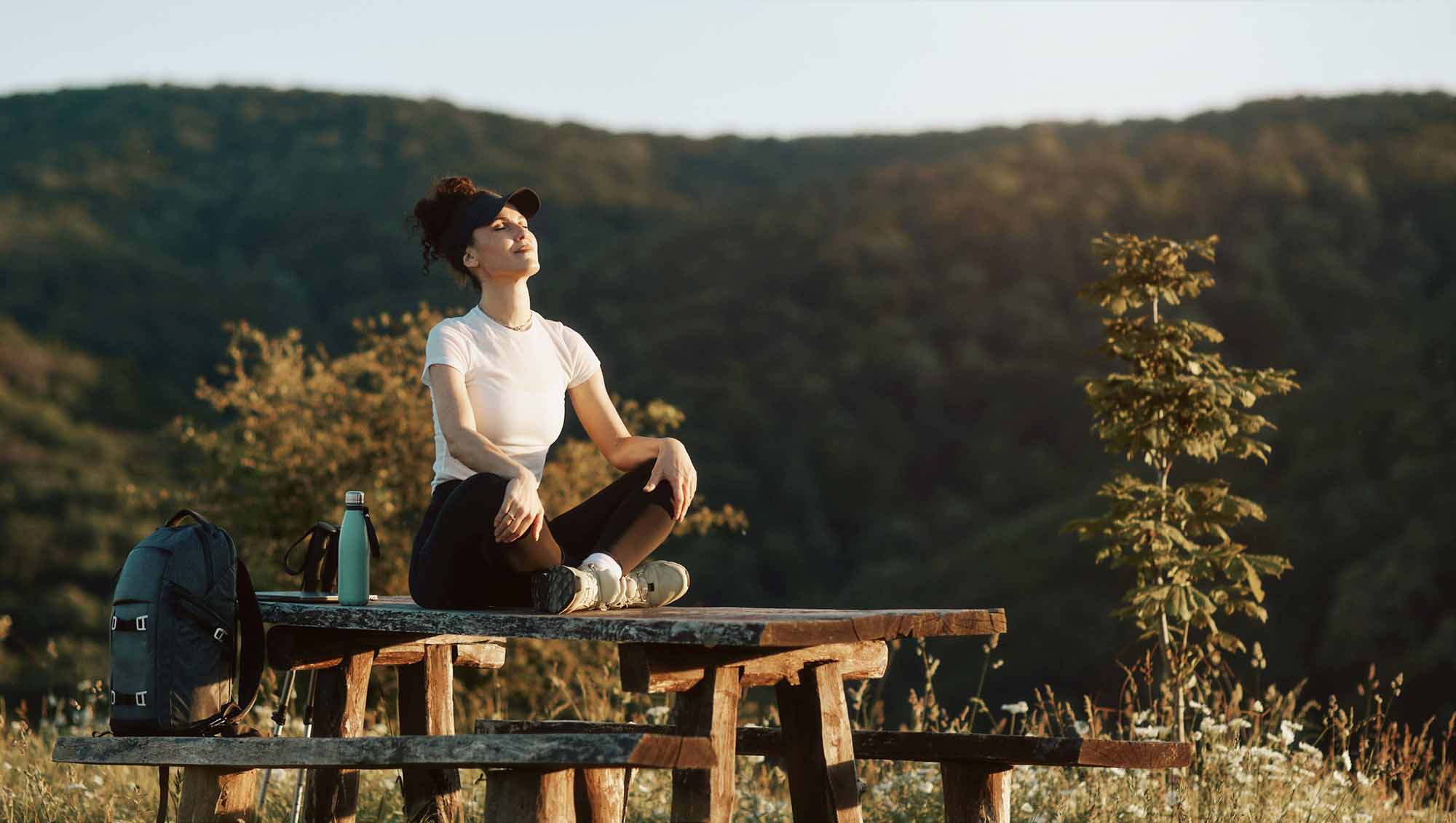 a woman rests on a picnic table during a hike