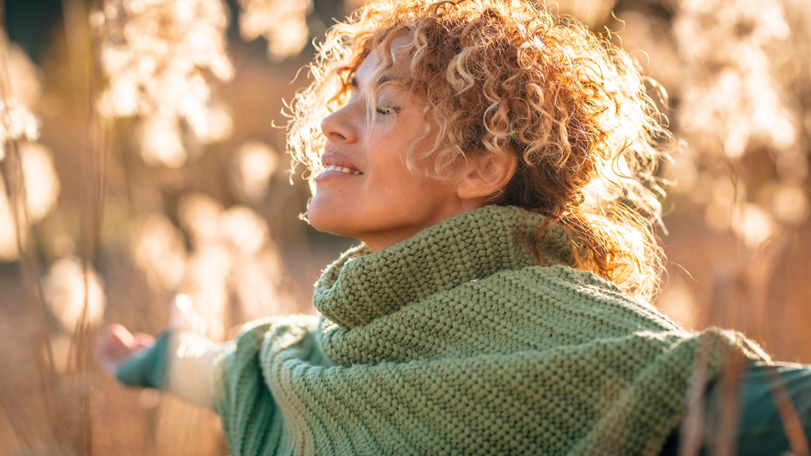 a woman stands with her arms open in a gorgeous field