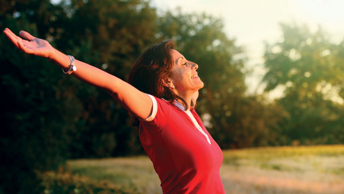a senior woman outside with her arms opened wide