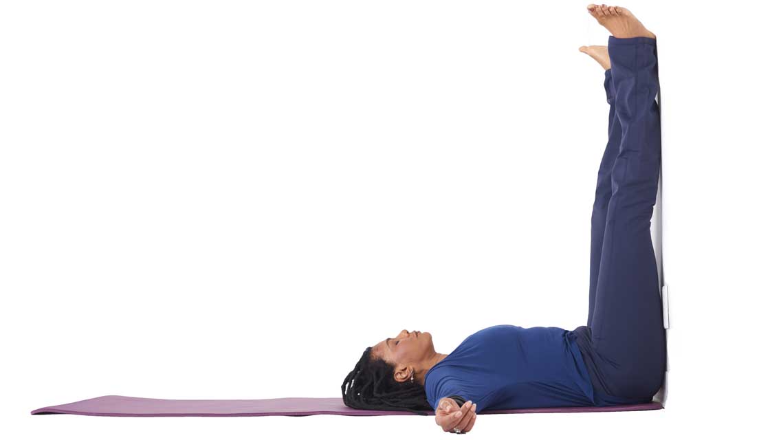 a woman lies on the floor with her legs up a wall