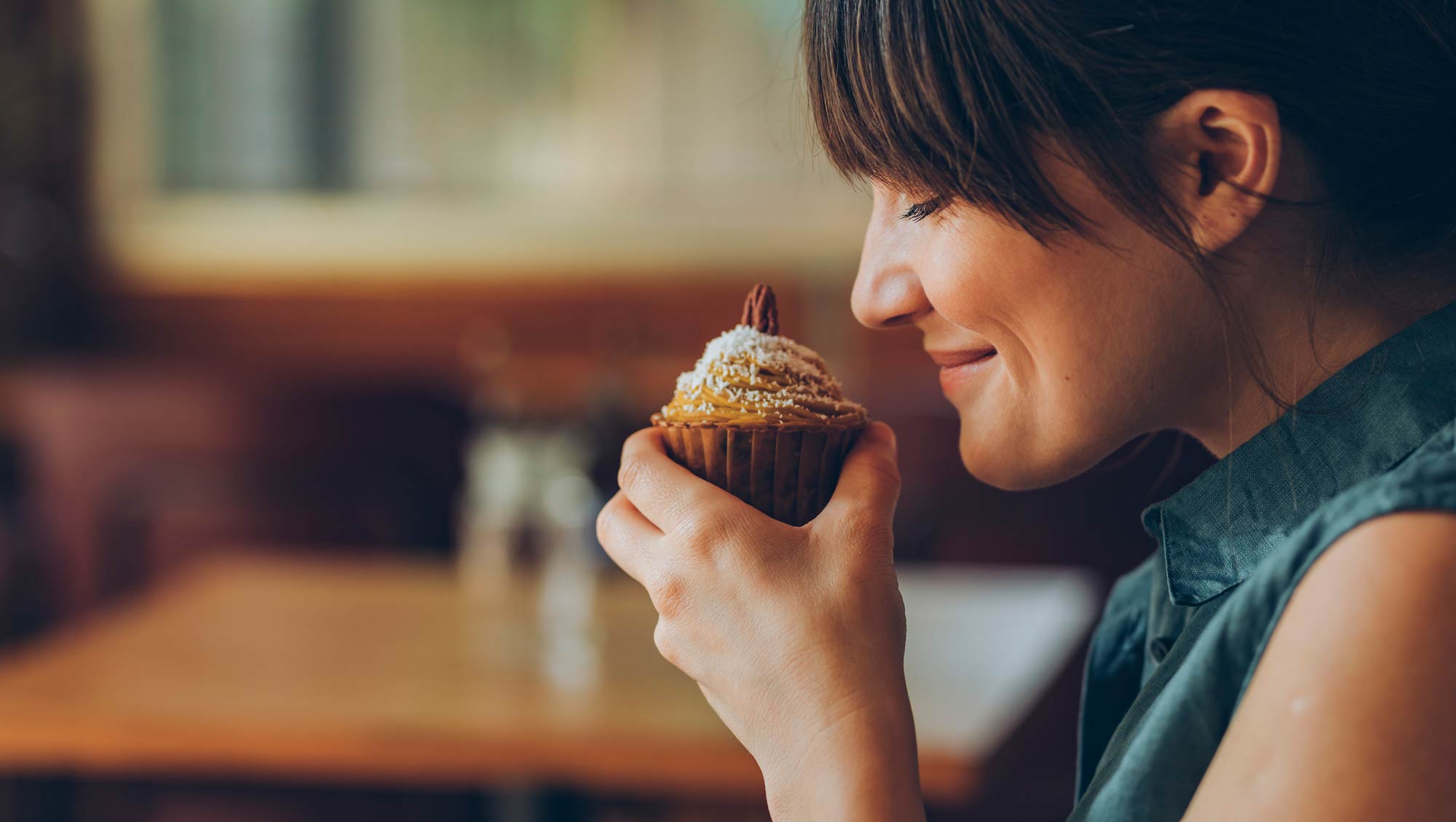 Happy Woman Enjoying the Aroma of a Delicious Pumpkin Spice Cupcake