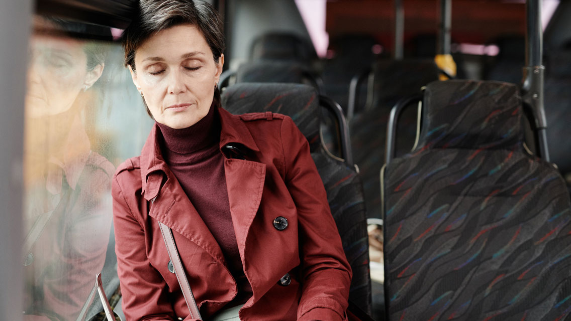 a woman rests with her eyes closed on a bus