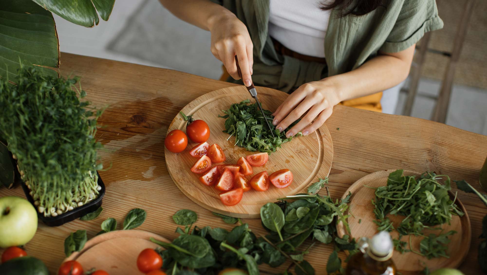 a woman chops tomatoes and arugula in her kitchen