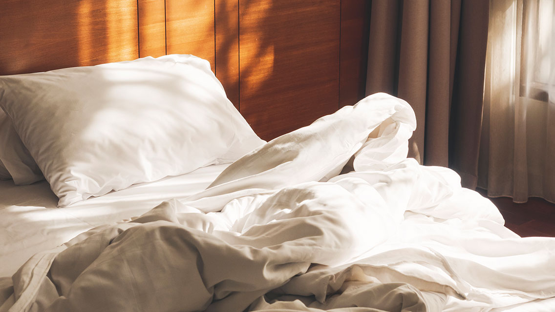 Unmade bed with morning sunlight